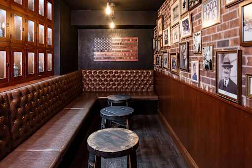 Private clubroom styled as a speakeasy with leather booths and brick gallery wall.