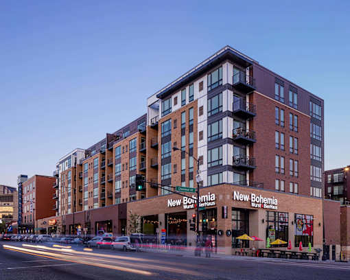 Exterior of Oxbo Urban Rentals with their large windows. Apartment units are located above a level of retail space, a restaurant on this level is New Bohemia.