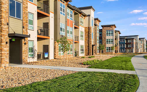 Parkhouse courtyard with green grass, rock beds and concrete walking path