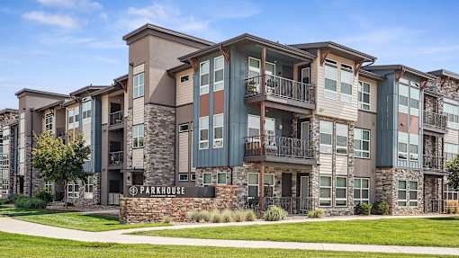 an apartment building with a green lawn and a sidewalk