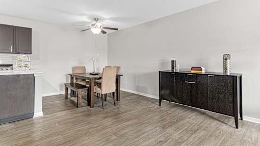 a dining room with a table and chairs and a kitchen with a cabinet