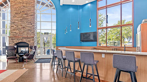 a lobby with a bar with chairs and a fireplace