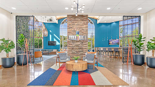 a lobby with a round table and chairs and a blue wall with a large window