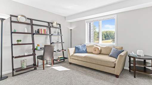 a living room with a couch and a desk and a window