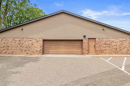 A building with a brown garage door and a brick wall.