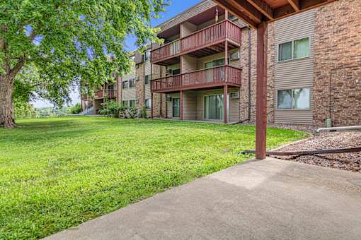A grassy area in front of a brick building with a tree.