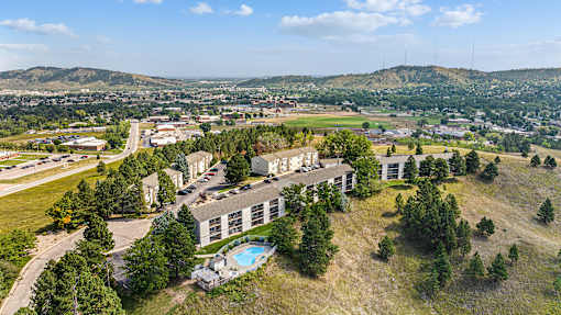 an aerial view of a building with trees and a city in the background