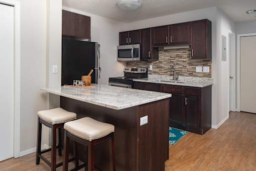 Stunning kitchen with breakfast bar, granite countertops and dark wood cabinets