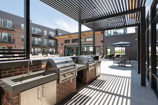 A patio with a grill and a table with chairs.