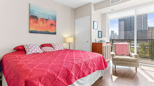 a bedroom with a red bed and a large window