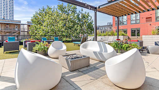 a rooftop patio with chairs and tables and a fire pit