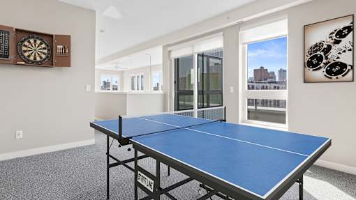 a games room with a ping pong table and a view of the city