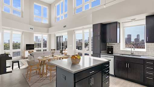 a kitchen with a large island and a living room with a table and chairs