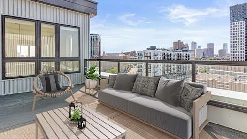 a balcony with a couch and a chair and a view of the city