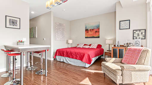 a bedroom with a red bed and a desk and a chair