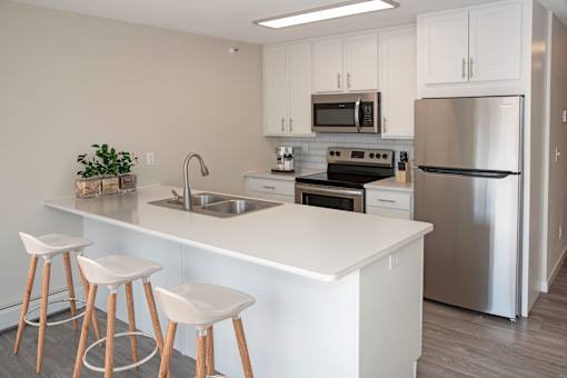 Studio unit with a modern kitchen featuring a breakfast bar and white cabinetry.
