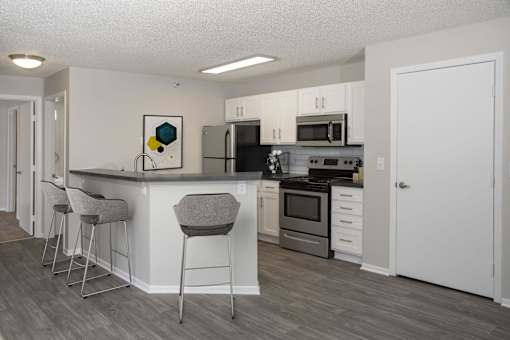 Modern kitchen with open layout, stainless steel appliances, and white cabinetry.