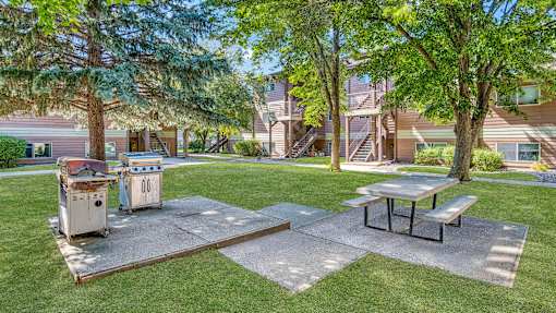 a picnic area with a grill and picnic table in front of a house