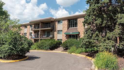 a picture of an apartment building with trees and bushes in front of it