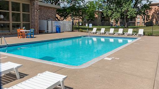 a swimming pool with chaise lounge chairs and trees in the background