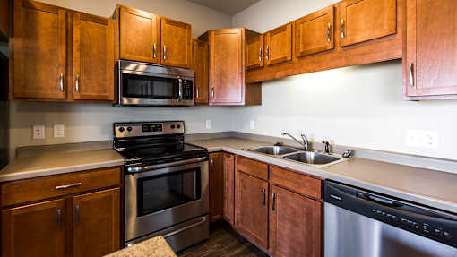 an empty kitchen with wooden cabinets and stainless steel appliances