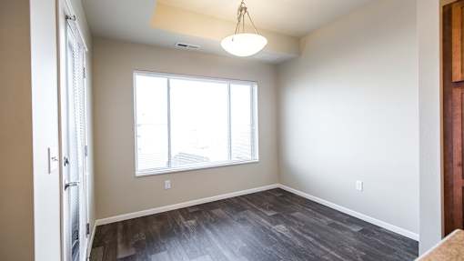 an empty living room with a large window and wood flooring