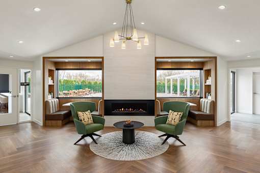A modern living room with a fireplace and two green chairs.