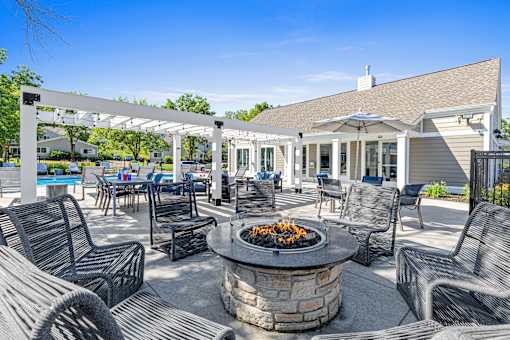 A patio with a fire pit and chairs.