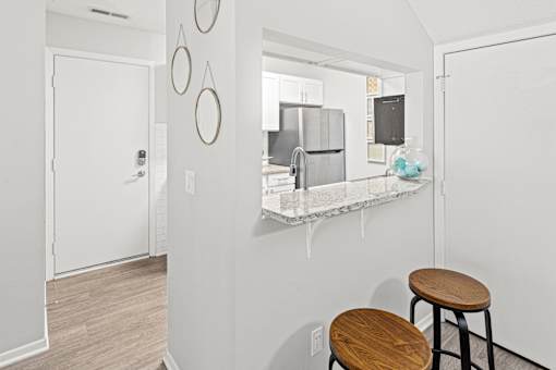 A kitchen with a bar stool in front of a counter.