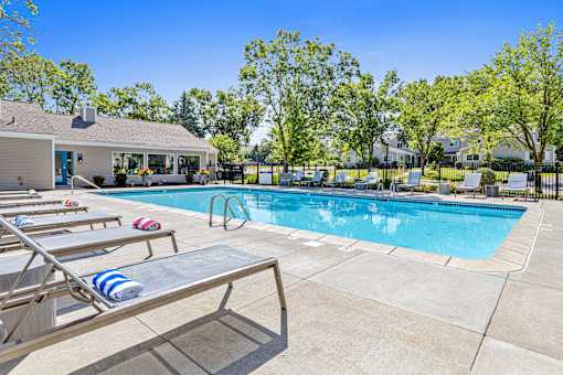 A pool with sun loungers and a house in the background.