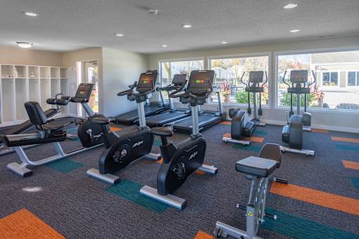 A gym with treadmills, stationary bikes, and dumbbells.