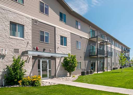 Exterior of Southpoint Apartments featuring grass lined sidewalk leading to the building. View of building showcases many windows and balconies lending ample natural light to the units.