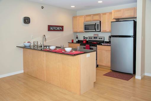 Kitchen with light wood cabinetry, large breakfast bar, and stainless steel finishes.