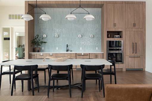 A modern kitchen with a glass backsplash and wooden cabinets.