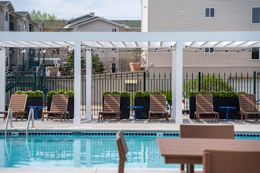 A pool with chairs and a table in the foreground.