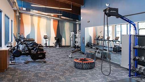 a gym with exercise equipment and a tire on the floor at The Bosk Apartment Homes, Woodbury
