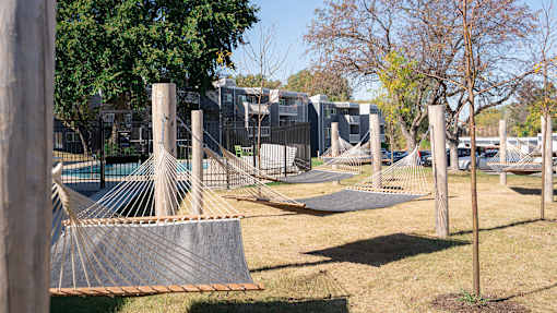 a playground with hammocks and a fence and houses in the background at The Bosk Apartment Homes, Woodbury, Minnesota