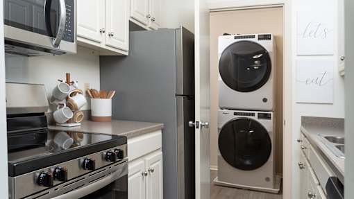 A modern kitchen with a stove, microwave, and a washing machine at The Bosk Apartment Homes, Woodbury, MN