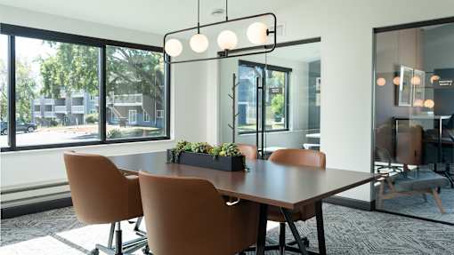 a conference room with a large window and a table with chairs at The Bosk Apartment Homes, Woodbury, 55125