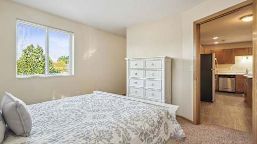 A bedroom with a large bed and a dresser with a mirror.