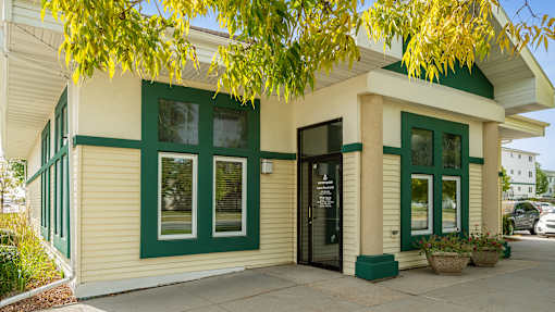 A small building with a green trim and a black door.