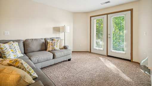 A living room with a grey couch and a lamp.