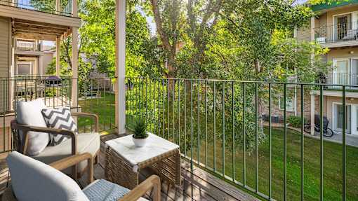 A patio with a table and chairs overlooks a green lawn.