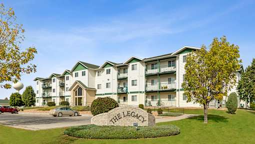 The Legacy apartment complex is surrounded by a grassy area and trees.