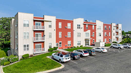 an exterior view of an apartment building with cars parked in a parking lot