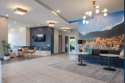a lobby with a couch table and chairs and a large mural on the wall