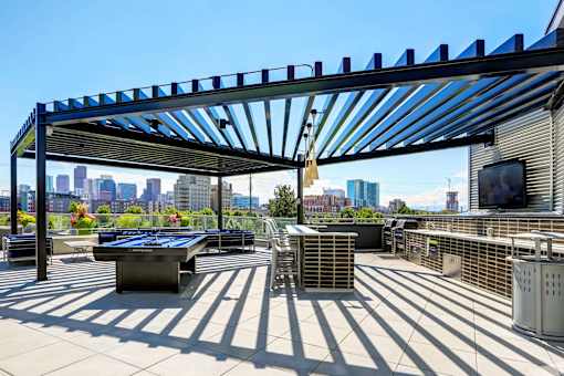 Sky deck at Westend Apartments featuring a full grilling station, billiards table, and island seating covered by a pergola.