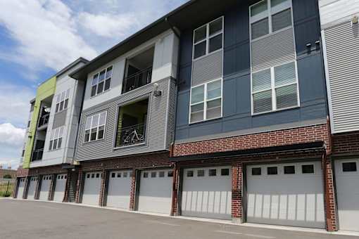 Private garages on ground level of the building with white doors and large driveway.