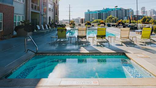 the pool on the rooftop of an apartment building with chairs around it