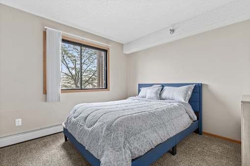 A bedroom with a bed, pillows, and a window.
